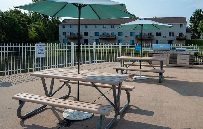 two picnic tables with umbrellas in a park