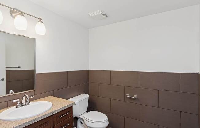 A bathroom with brown tiles and a white toilet.