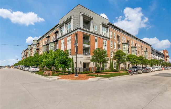 A street view of a row of red brick apartment buildings with cars parked in front.
