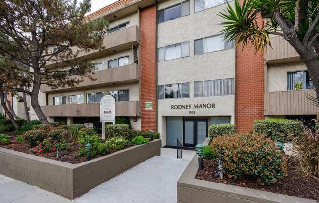 an apartment building with a sidewalk and garden in front of it