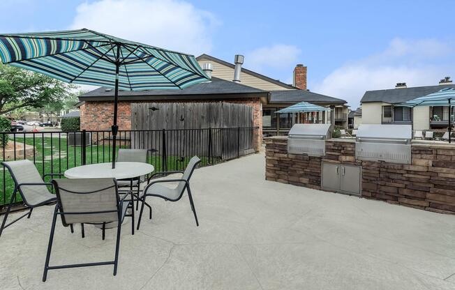 stainless steel barbecues next to a table and chairs