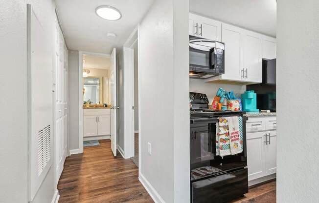a renovated kitchen with white cabinets and a black stove and microwave at The Glen at Highpoint, Dallas, 75243