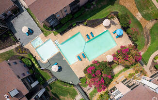 A swimming pool surrounded by a grassy area and a few trees.