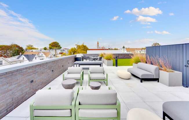 a rooftop terrace with couches and tables and a brick wall