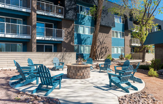 a fire pit with adirondack chairs in front of an apartment building