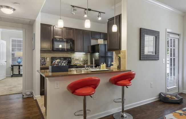 kitchen with brown cabinetry, pendant and tracking lighting, and breakfast bar