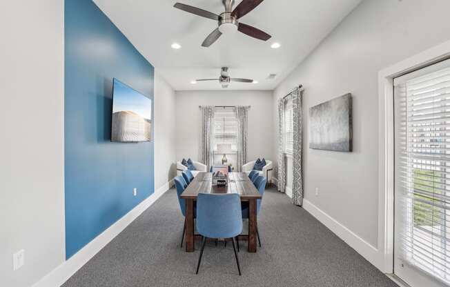 A dining room with a blue wall and a ceiling fan.
