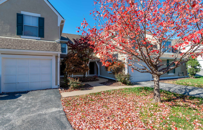 a tree with red leaves in front of a house