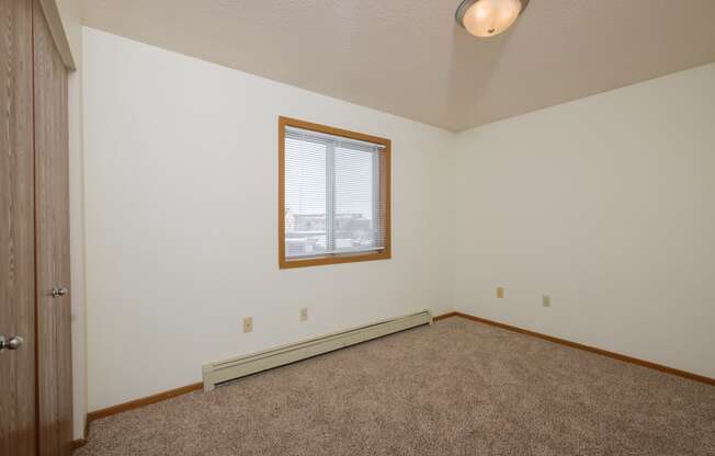 the bedroom  with carpet and a window. Fargo, ND Park Circle Apartments.