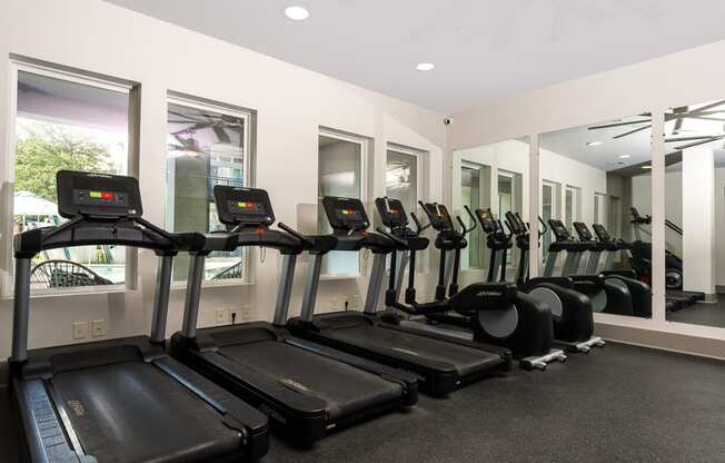 a row of treadmills and elliptical trainers in a gym