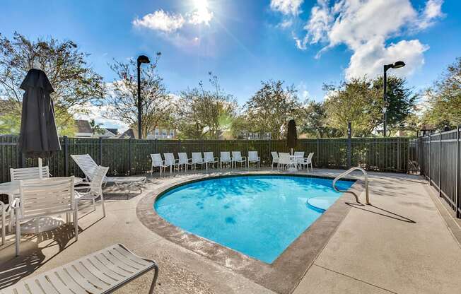 A sunny day at the pool with chairs and umbrellas.