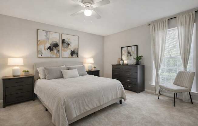 A bedroom with a large bed, a dresser, and a chair.