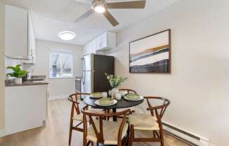 A dining room with a table set for two and a ceiling fan.