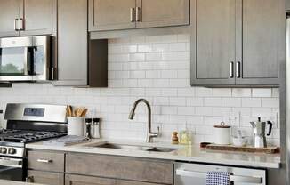 a kitchen with gray cabinets and white tile