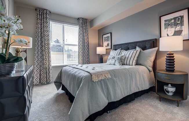 A bedroom with a large bed and a nightstand with a lamp.