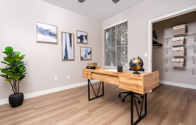 a home office with a wooden desk and a large window