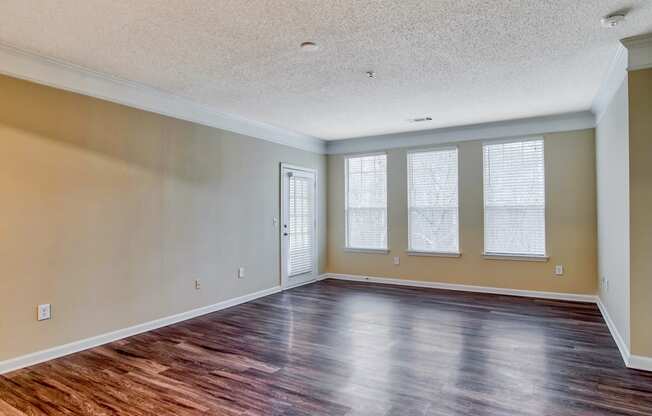 a bedroom with hardwood floors and three windows