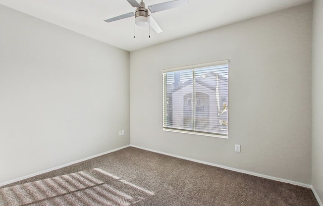 A room with a ceiling fan and a window with blinds.