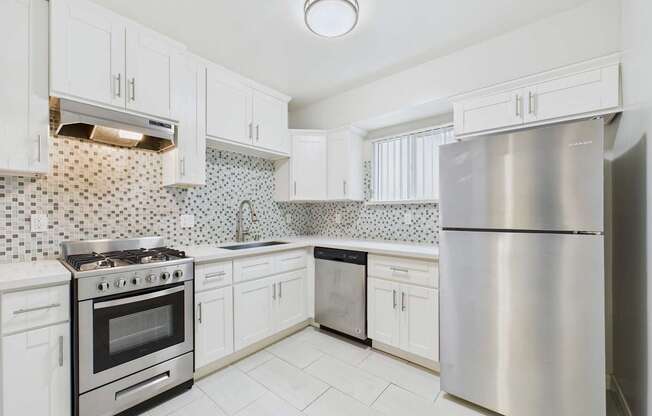 A kitchen with white cabinets and a stainless steel refrigerator.