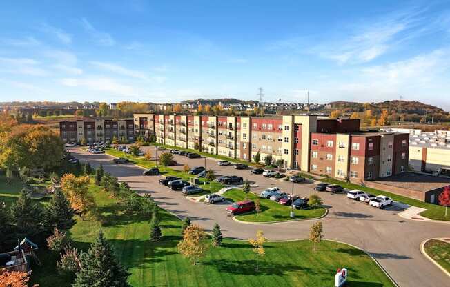A large apartment complex with a parking lot in front.