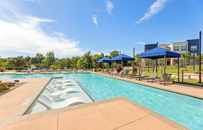 A large outdoor swimming pool with a slide and sunshades.