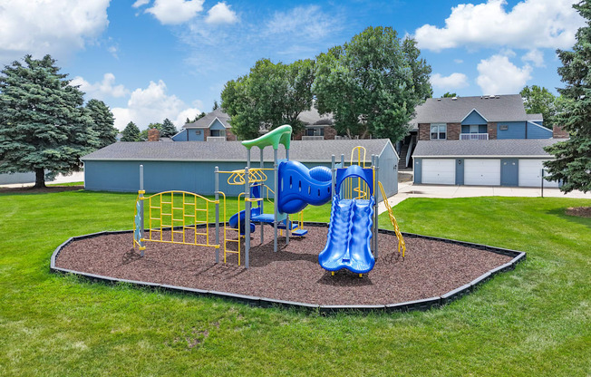 A playground with a blue slide and yellow safety barriers.