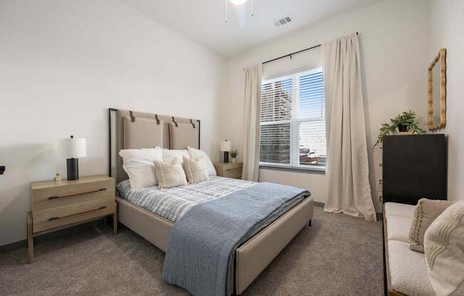 A bedroom with a bed, nightstand, and chair.