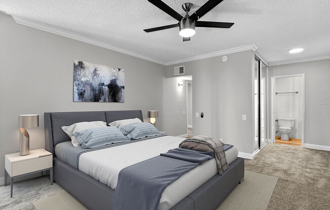 Carpeted bedroom with ceiling fan and private bathroom.