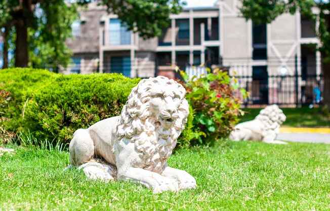 A white lion statue is sitting on the grass in front of a building.