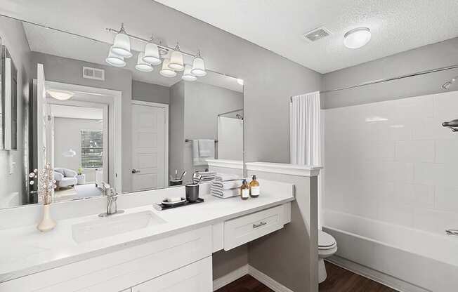 Model Bathroom with White Cabinets, Wood-Style Flooring & Shower/Tub at Fountains Lee Vista Apartments in Orlando, FL.