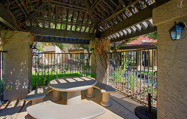 a patio with a table and chairs and a fence