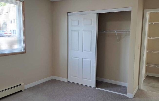 a closet with a white door in a room with a window