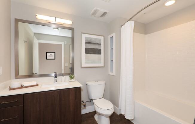 a bathroom with a toilet sink and mirror and a shower