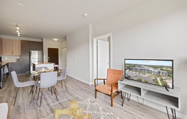 a living room with a tv and a dining room in the background