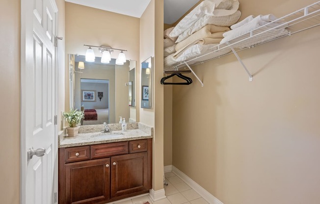 a bathroom with a sink and a mirror and a closet with towels