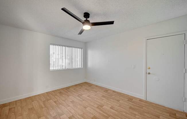 A room with a ceiling fan and wooden flooring.