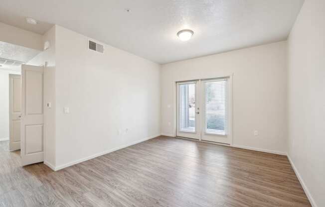 the living room of an apartment with white walls and wood floors