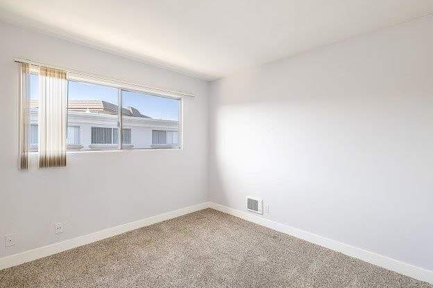 A room with a window and a carpeted floor.