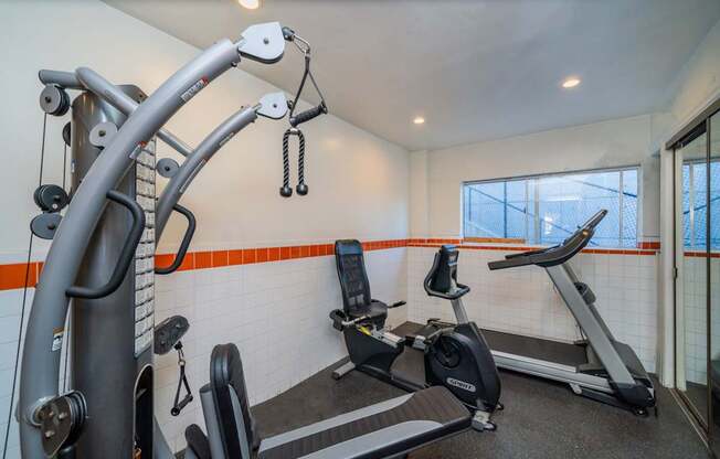 A gym with a treadmill, elliptical trainer and a stationary bike.