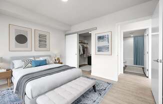 A bedroom with a large bed and a bench in the middle of the room.