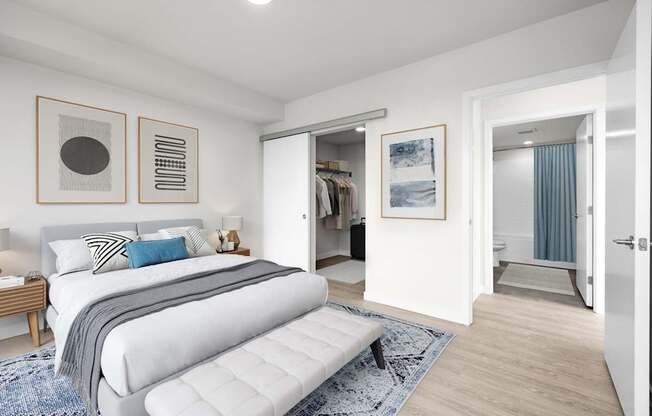 A bedroom with a large bed and a bench in the middle of the room.