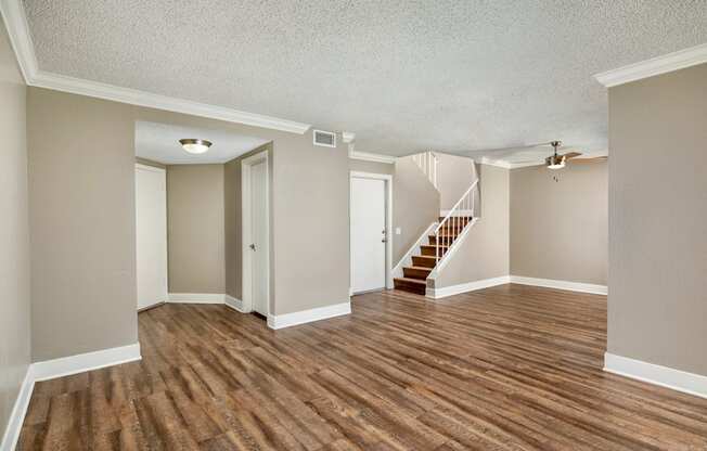 A living room with hardwood floors and a staircase and ceiling fan.