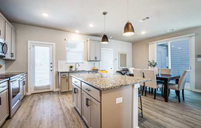 Canvas at Denton spacious kitchen with hardwood style flooring stainless steel appliances large island and granite countertops, build to rent, homes for rent in Denton, professionally managed rental home community, private yards, low maintenance, pet-friendly.