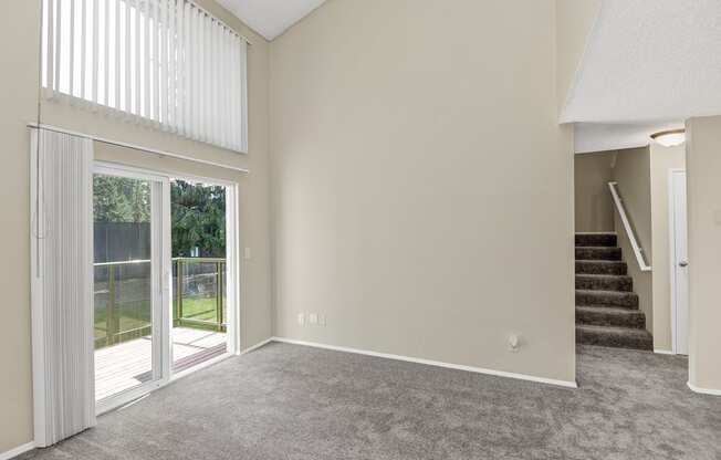 an empty living room with a sliding glass door leading to a patio