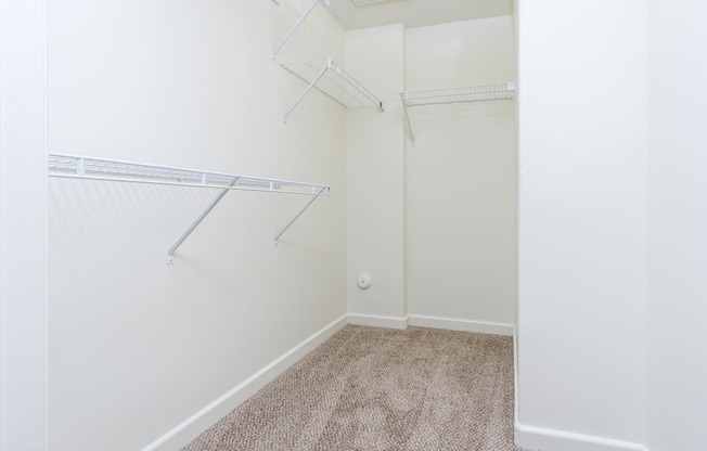 a bedroom with white walls and a white closet with white shelves