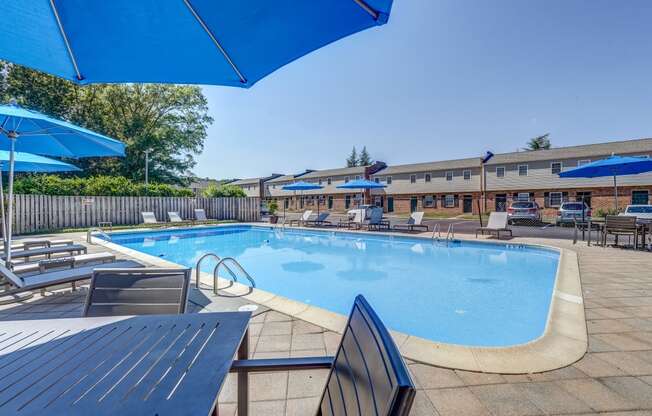 our resort style swimming pool is surrounded by chairs and umbrellas