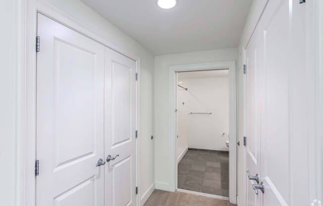 A white hallway with a door on the left and a bathroom on the right with plenty of storage at 7 Cameron Apartments, Massachusetts, 02140