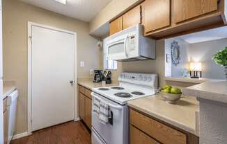 A kitchen with a white stove and a white door.