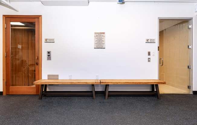 a wooden bench in front of a white wall with a door