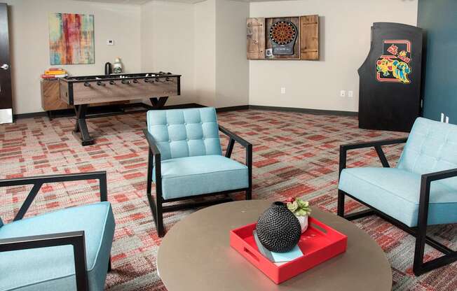 A room with a foosball table and two chairs.
